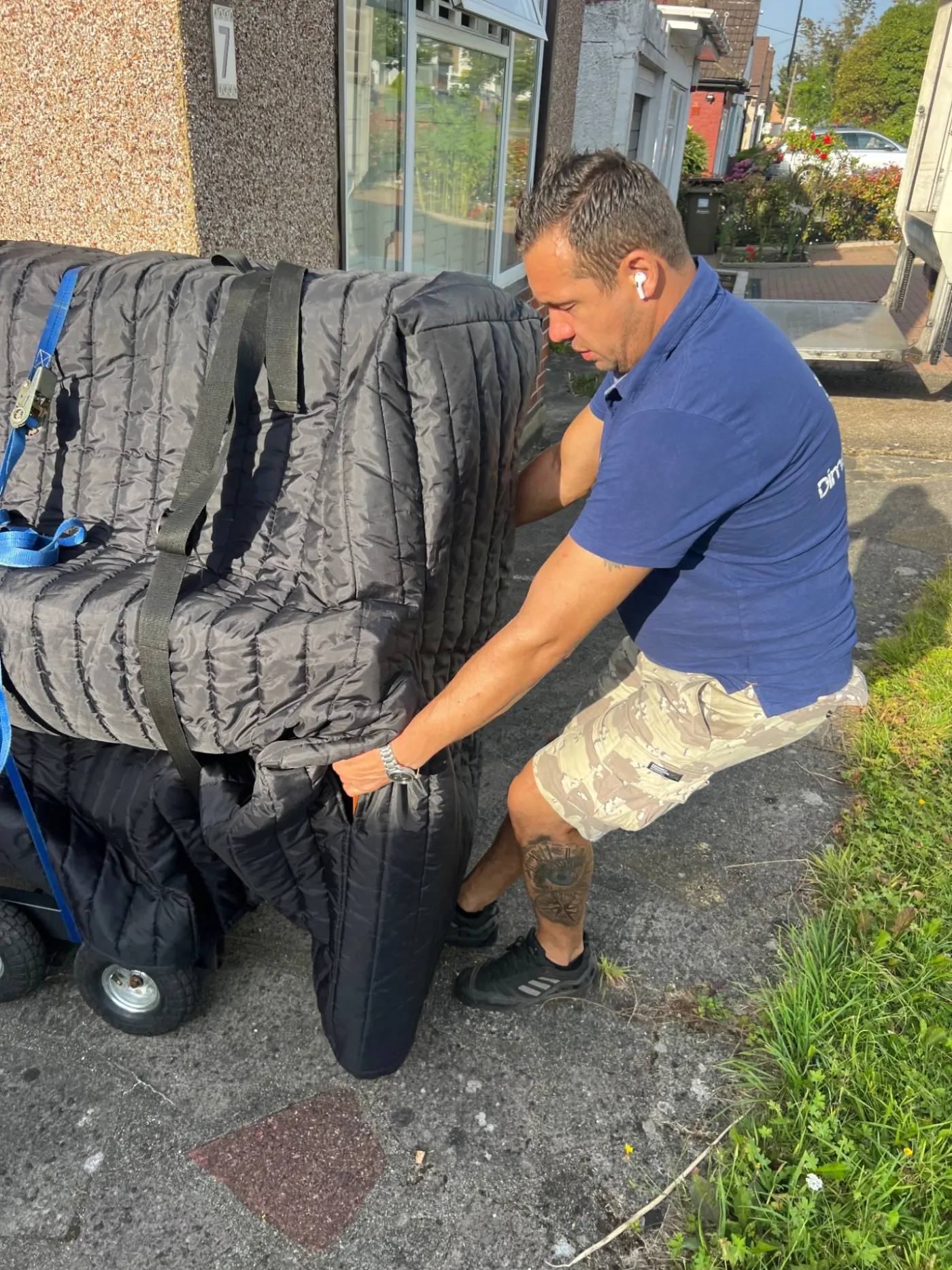 Dimond Movers crew loading a wrapped piano onto a piano dolly outside a property