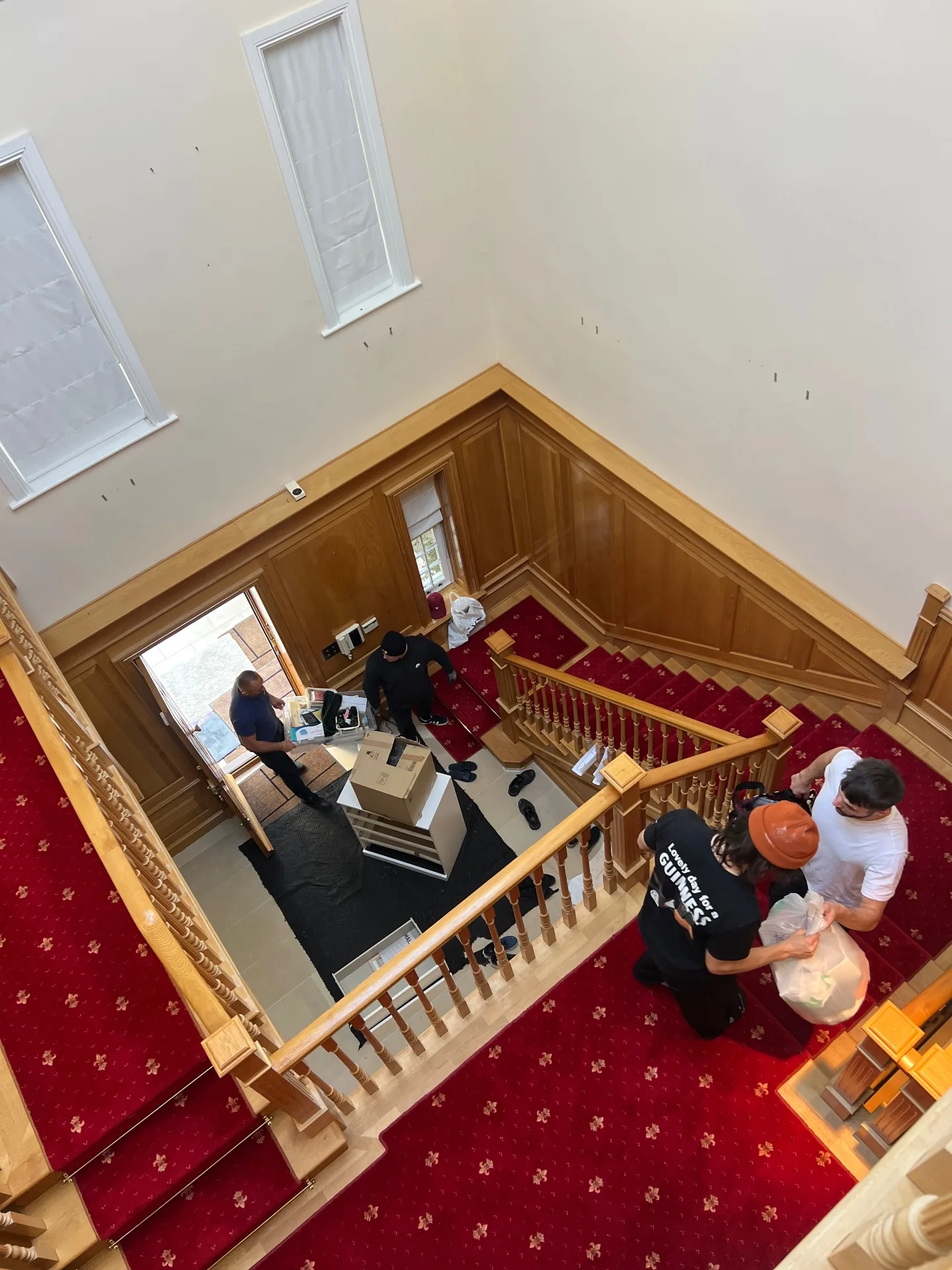 Dimond Movers team carrying boxes and bags through a grand oak-panelled staircase hallway during a UK house move