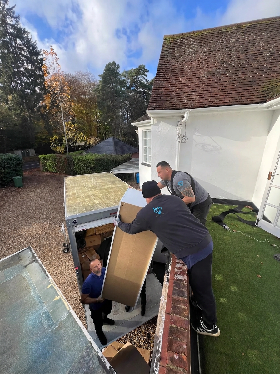Three Dimond Movers crew members coordinating to load furniture into the removals van on a UK house move